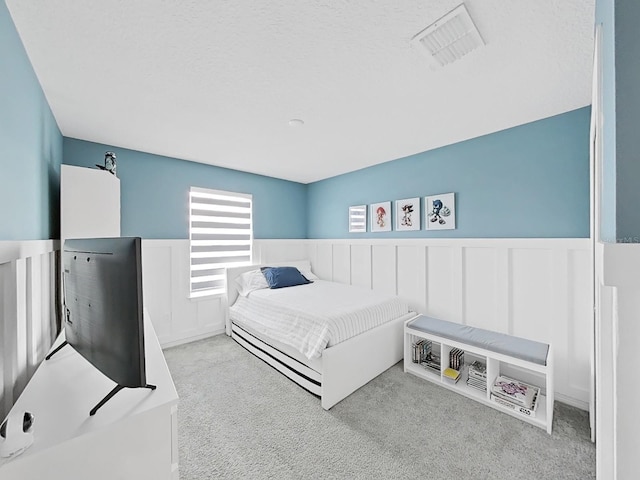 17737 Everlong Dr, Land O Lakes, FL 34638 - bedroom with carpet flooring, a textured ceiling, visible vents, and wainscoting