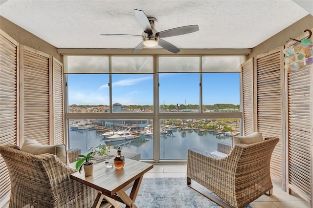 sunroom / solarium featuring a water view, a textured ceiling, floor to ceiling windows, and tile patterned flooring