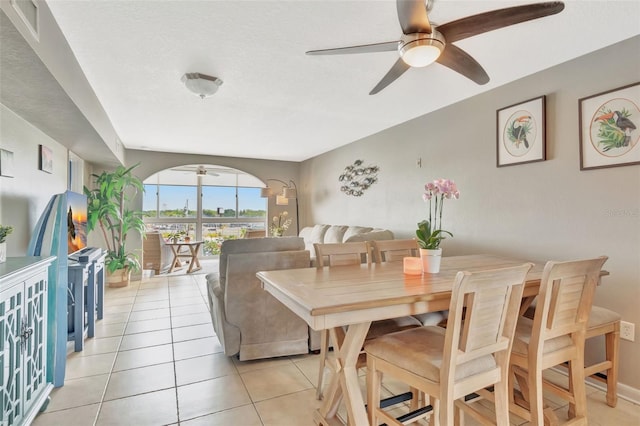 dining room featuring arched walkways, ceiling fan, and light tile patterned floors