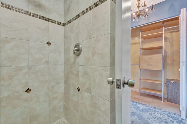 bathroom featuring an inviting chandelier, tile patterned floors, and tiled shower