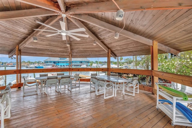 wooden terrace with outdoor dining area, a water view, and ceiling fan