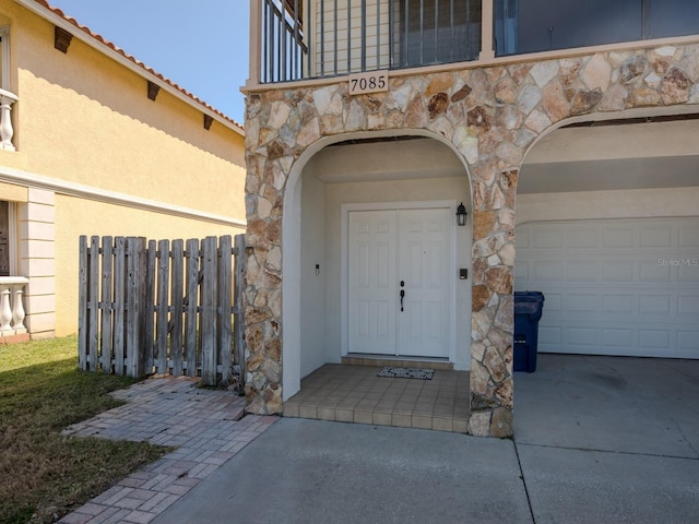 7085 Sunset Dr S Unit A, Saint Petersburg, FL 33707 - view of exterior entry with stone siding, a garage, and stucco siding