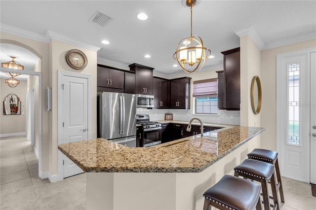 4610 Alexandria Ct, Palmetto, FL 34221 - kitchen with dark brown cabinetry, visible vents, appliances with stainless steel finishes, a peninsula, and a notable chandelier