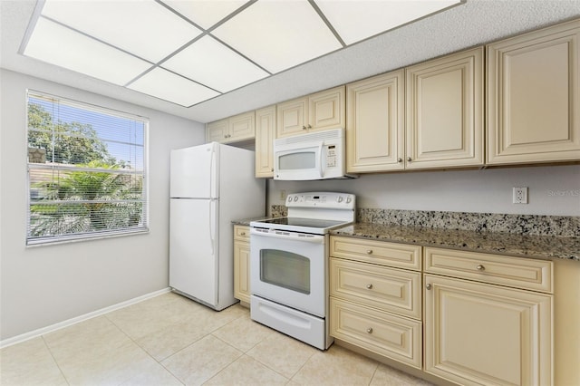 kitchen featuring white appliances, baseboards, a healthy amount of sunlight, and cream cabinetry