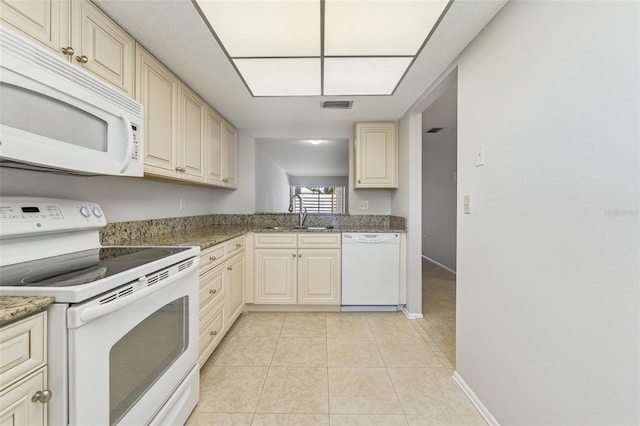kitchen with a sink, cream cabinetry, and white appliances