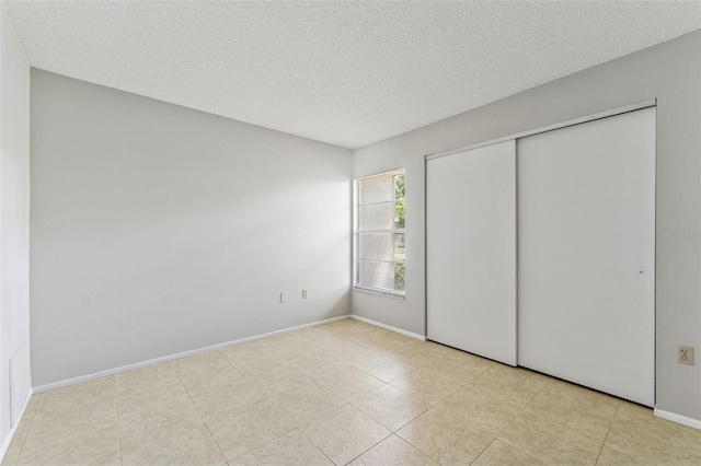 unfurnished bedroom featuring a closet, a textured ceiling, and baseboards