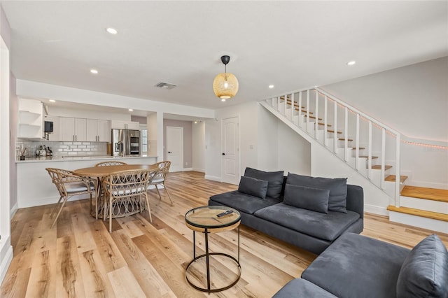 living room featuring visible vents, stairs, baseboards, recessed lighting, and light wood-type flooring