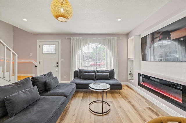 living area with recessed lighting, light wood-type flooring, stairs, and a wealth of natural light