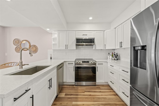 kitchen with appliances with stainless steel finishes, open shelves, a sink, white cabinets, and recessed lighting