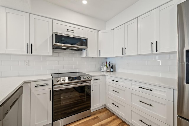 kitchen with decorative backsplash, white cabinetry, and stainless steel appliances