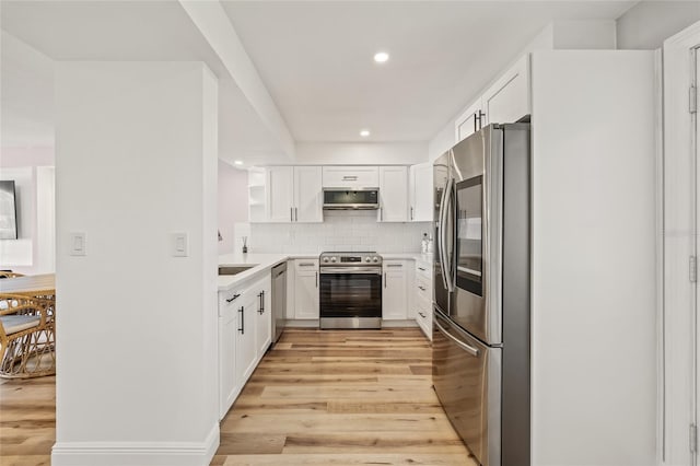 kitchen featuring white cabinets, stainless steel appliances, decorative backsplash, and light wood finished floors
