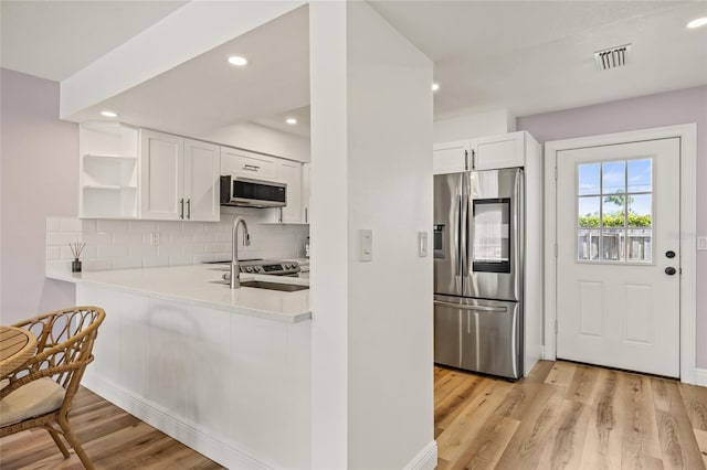 kitchen featuring light wood-type flooring, open shelves, white cabinetry, and appliances with stainless steel finishes