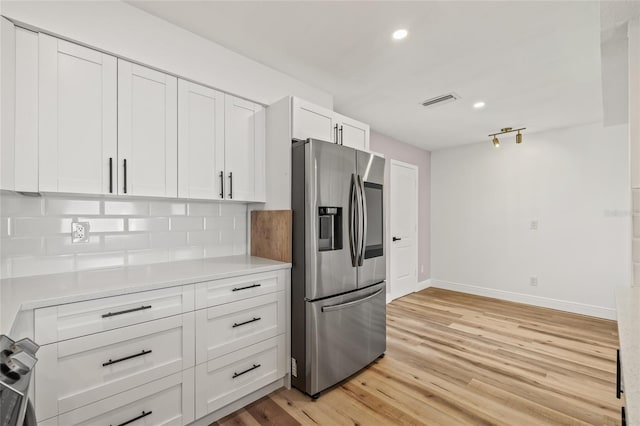 kitchen with white cabinets, light countertops, baseboards, light wood-type flooring, and stainless steel refrigerator with ice dispenser