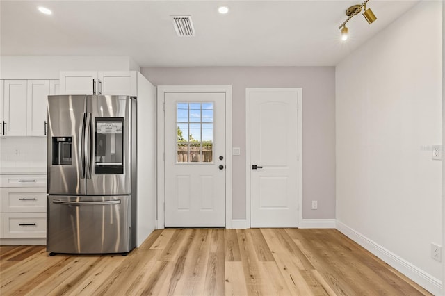 kitchen featuring white cabinets, stainless steel fridge, light wood-style floors, baseboards, and visible vents