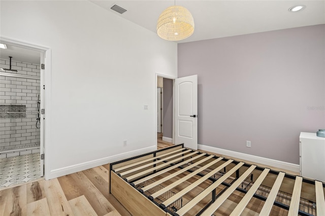 unfurnished bedroom with baseboards, visible vents, wood finished floors, and ensuite bathroom