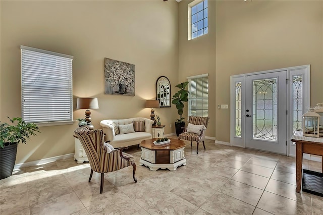 living room featuring baseboards and a towering ceiling
