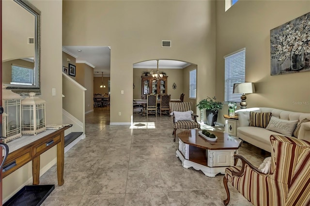living area with crown molding, arched walkways, a high ceiling, and a chandelier