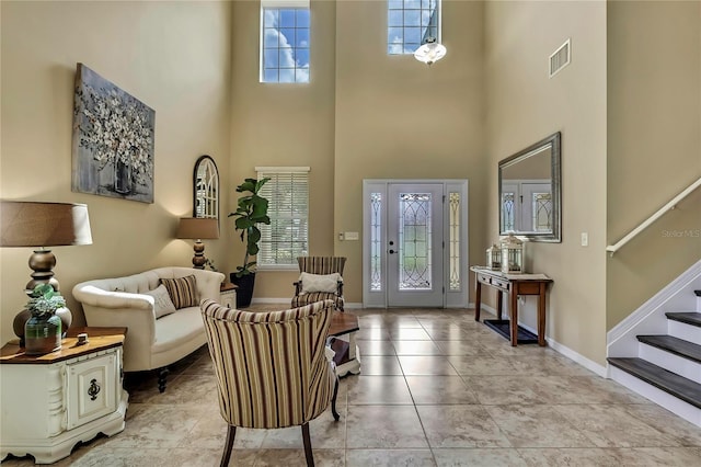 entryway with stairs, visible vents, a wealth of natural light, and a towering ceiling