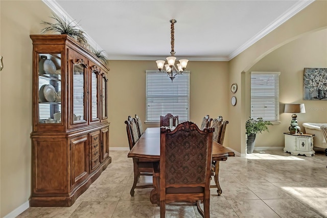 dining area with crown molding, arched walkways, baseboards, and an inviting chandelier