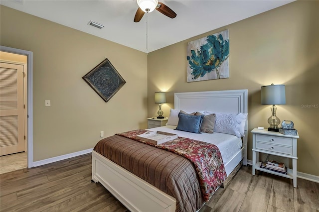 bedroom with a ceiling fan, baseboards, visible vents, and wood finished floors