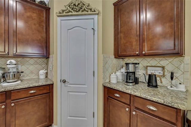 kitchen with decorative backsplash, light stone countertops, and dark brown cabinets
