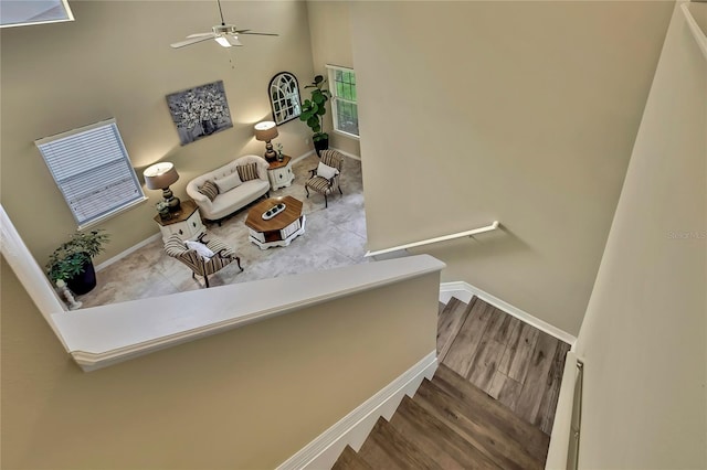 stairway with a ceiling fan, baseboards, and wood finished floors
