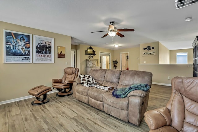 living area with baseboards, a ceiling fan, wood finished floors, and visible vents