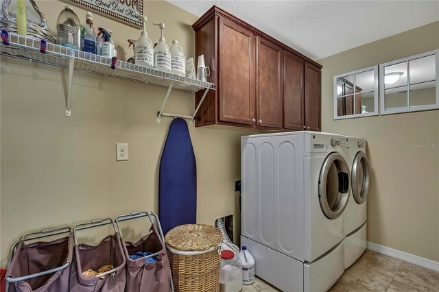 washroom with baseboards, cabinet space, and washing machine and clothes dryer