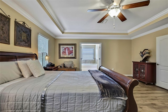 bedroom featuring crown molding, a raised ceiling, wood finished floors, and visible vents