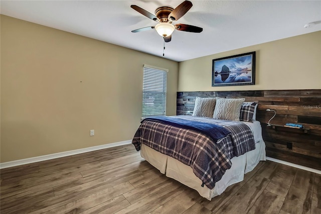 bedroom featuring a ceiling fan, baseboards, and wood finished floors