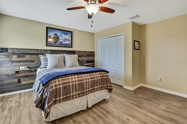 bedroom featuring baseboards, a closet, wood finished floors, and visible vents