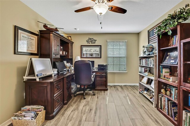 home office with light wood-style floors, baseboards, and a ceiling fan