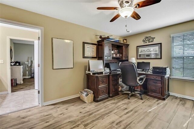 home office with a ceiling fan, baseboards, and light wood-type flooring