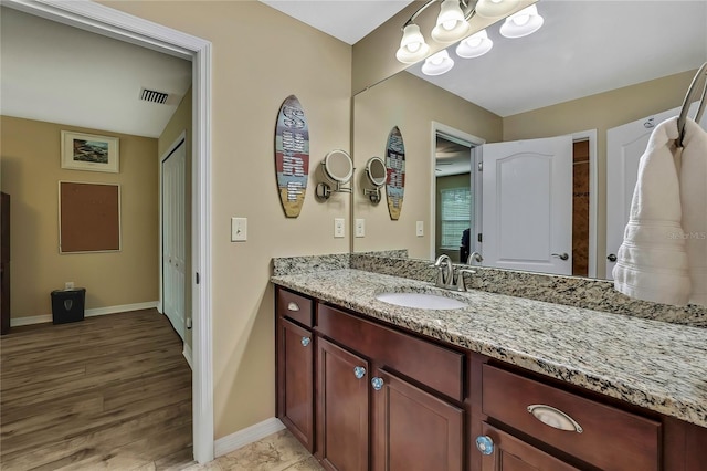 bathroom with baseboards, vanity, wood finished floors, and visible vents