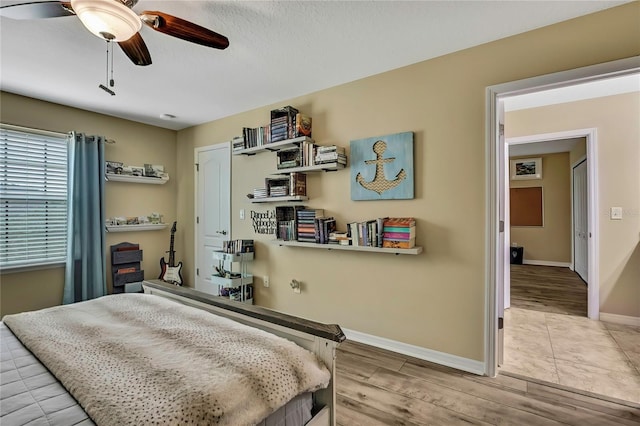 bedroom with a ceiling fan, baseboards, and wood finished floors