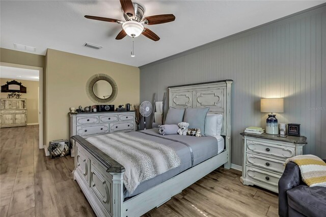 bedroom featuring visible vents, crown molding, wood finished floors, and ceiling fan