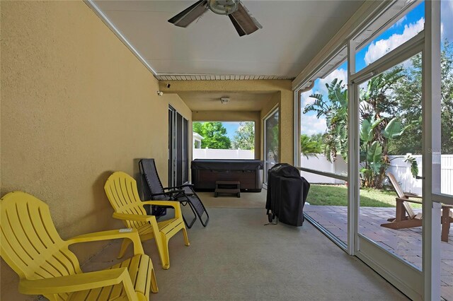 sunroom / solarium with carpet floors, a ceiling fan, a textured wall, and a jacuzzi