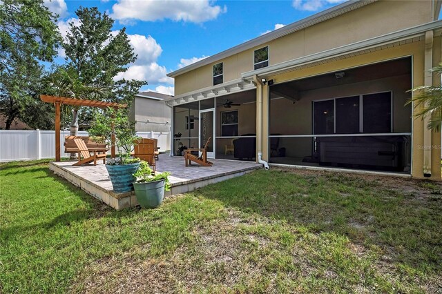 back of house featuring fence, stucco siding, a sunroom, a ceiling fan, and a yard