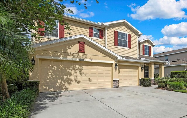view of front facade with an attached garage, driveway, stone siding, and stucco siding