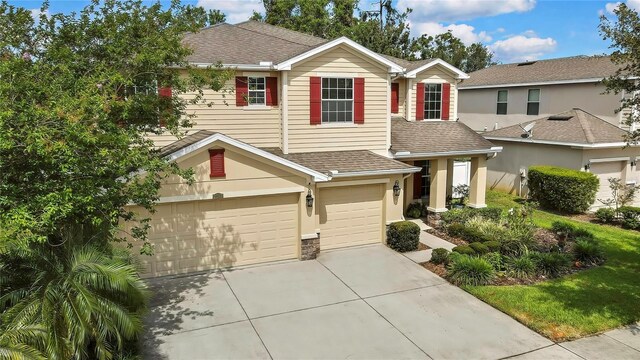 traditional home featuring concrete driveway, a shingled roof, and a garage