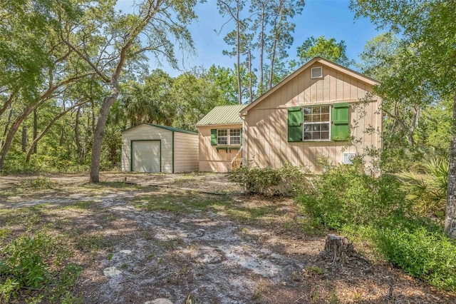 526 Kings Creek Cir, Steinhatchee, FL 32359 - exterior space featuring a garage, driveway, an outbuilding, metal roof, and a storage shed