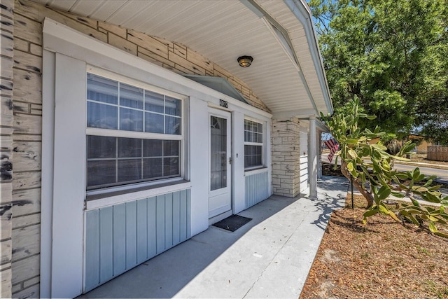 property entrance with board and batten siding and stone siding