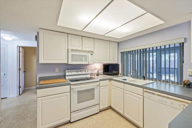 kitchen with white appliances, white cabinetry, and a sink