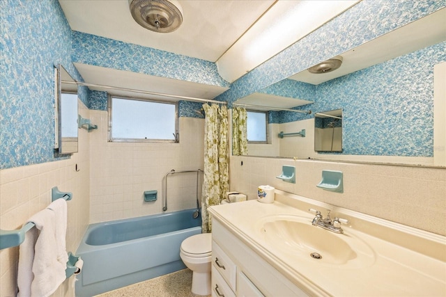 full bathroom featuring wainscoting, vanity, toilet, wallpapered walls, and tile walls