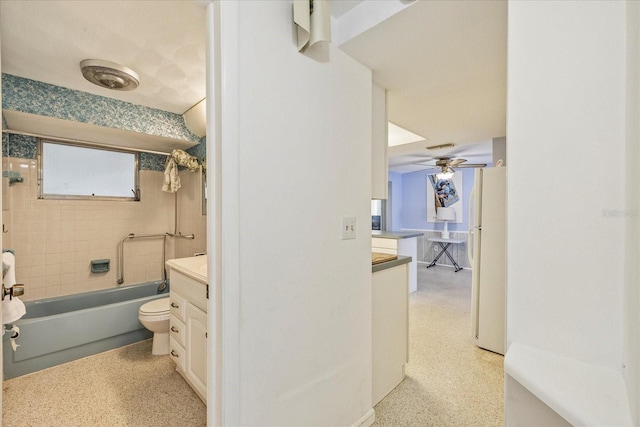 full bath featuring a ceiling fan, speckled floor, vanity, toilet, and tub / shower combination
