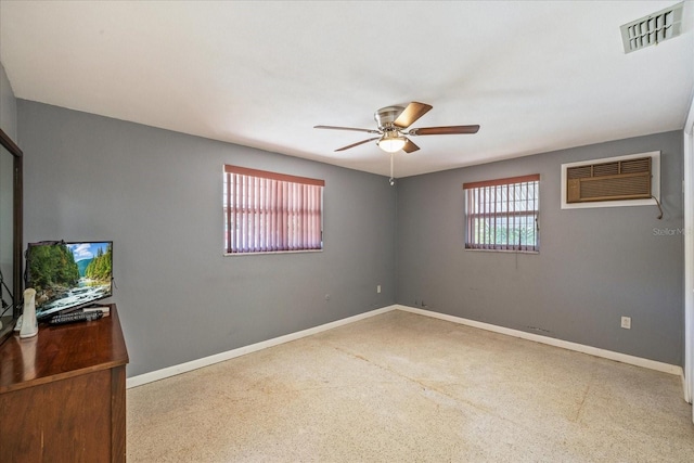 unfurnished room with baseboards, ceiling fan, a wall unit AC, and visible vents