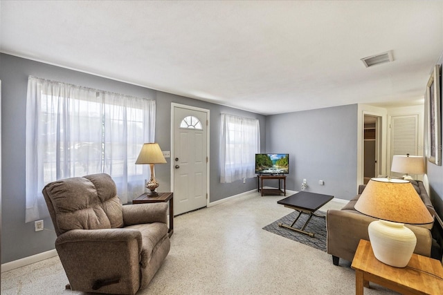 living room featuring baseboards, visible vents, and light speckled floor