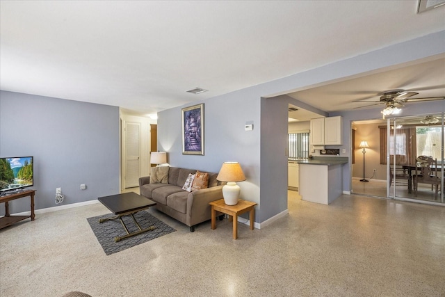 living area featuring visible vents, a ceiling fan, baseboards, and light speckled floor