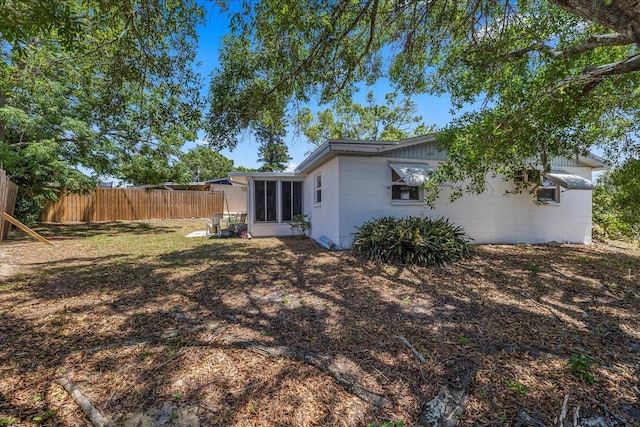 exterior space with fence, a sunroom, and concrete block siding