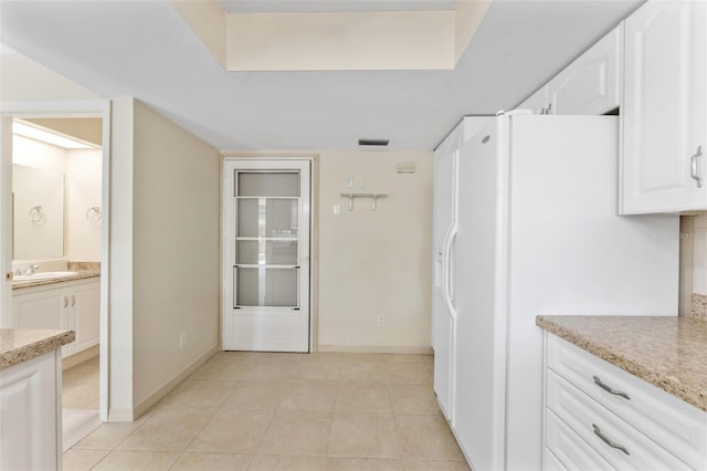 14506 Alejo Ct, Seminole, FL 33776 - kitchen with white refrigerator with ice dispenser, white cabinetry, a sink, light tile patterned flooring, and baseboards
